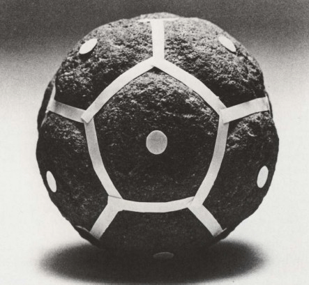 Каменный додекаэдр со скругленными гранями и ямками в центре (они для большей четкости отмечены полосками и кружками из бумаги).
